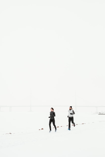 Photo gens de loin qui courent dans la neige