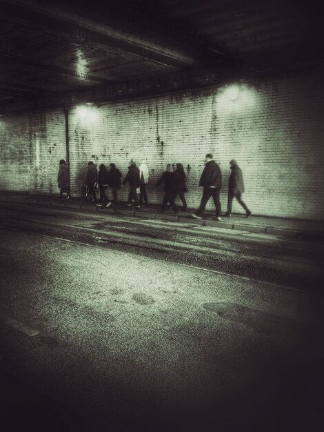 Photo des gens marchent dans un tunnel éclairé.