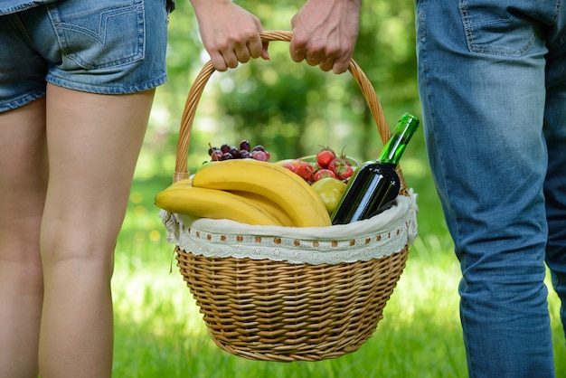 Les gens marchent en pique-nique dans le parc, tenant un panier de nourriture.