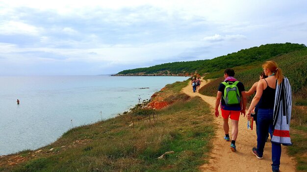 Des gens marchent sur le sentier de la mer à Minorque contre un ciel nuageux