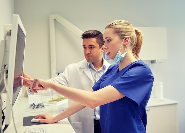 les gens, la médecine, la stomatologie, la technologie et le concept de soins de santé - les dentistes cherchent à scanner aux rayons X sur le moniteur à la clinique dentaire