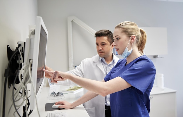 les gens, la médecine, la stomatologie, la technologie et le concept de soins de santé - les dentistes cherchent à scanner aux rayons X sur le moniteur à la clinique dentaire