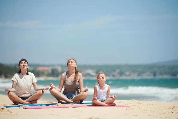 Gens méditant sur la plage