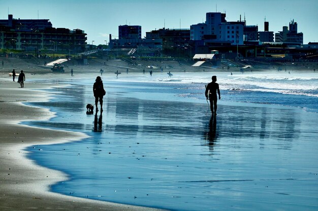 Photo des gens sur la mer par ville contre le ciel