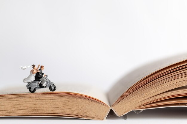 Des gens en miniature Un couple sur une moto sur un vieux livre