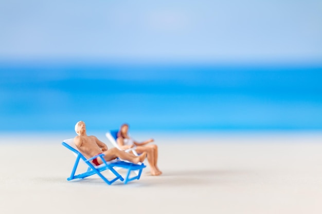 Des gens en miniature Un couple se détend sur des chaises de plage sur la plage