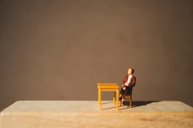 Photo gens de miniature, femme assise sur un bloc de bois en utilisant comme concept d'entreprise