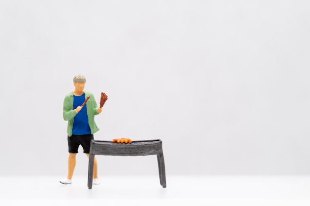 Photo des gens en miniature. un jeune homme au barbecue.