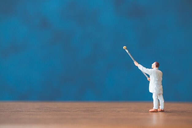 Photo des gens en miniature tenant un pinceau devant un fond de mur bleu