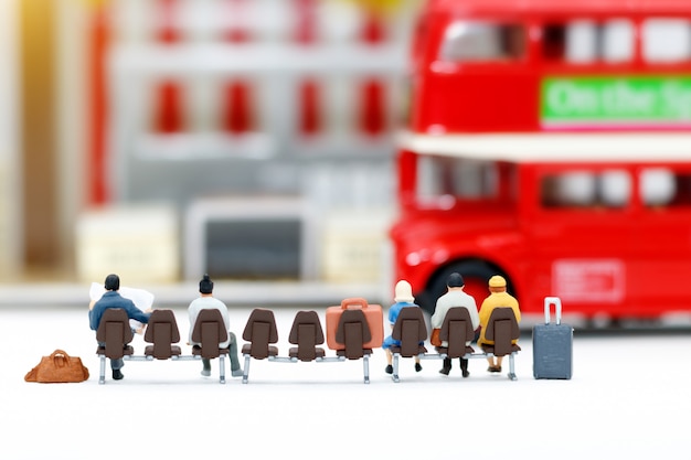 Gens miniatures avec des bagages en attente de bus. Concepts de transport.