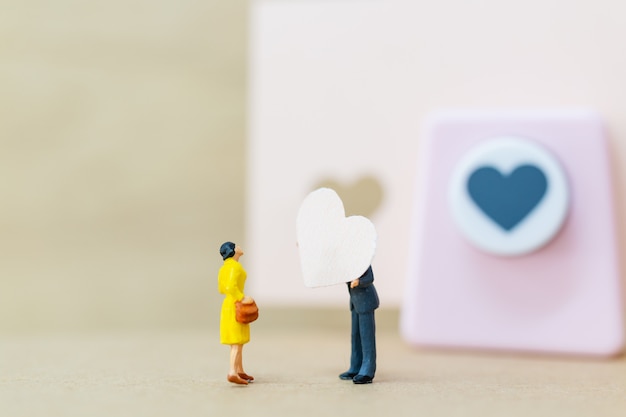 Gens miniatures: Couple avec coeur en papier sur fond de bois