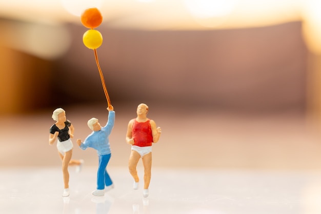 Gens miniatures famille heureuse courir et jouer avec ballon, concept d'enfance et de famille.