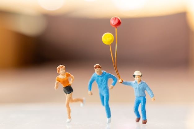 Gens miniatures famille heureuse courir et jouer avec ballon, concept d'enfance et de famille.