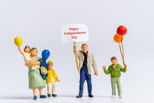 Gens miniatures tenant des drapeaux avec le mot Happy Independence Day