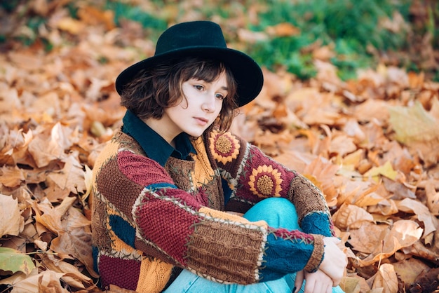 Les gens de la mode Girl in autumn orange leaves Outdoor Young hipster woman in a swe tricoté à la mode