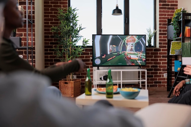 Les Gens Modernes S'amusent à Jouer à Des Jeux Vidéo De Tir, En Utilisant La Console De Télévision Et Le Contrôleur Pour Jouer à La Compétition De Jeux. Amis Profitant D'une Fête à La Maison Avec De La Bière Et Des Collations, Activité De Divertissement.