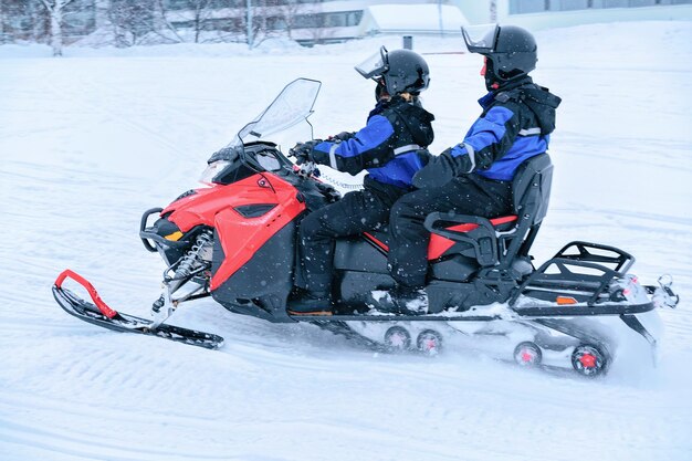 Les gens montent une motoneige dans le lac de neige gelé en hiver Rovaniemi, Laponie, Finlande