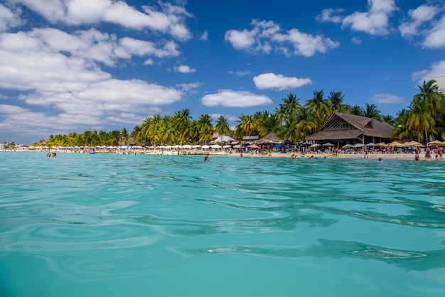 Les gens nagent près de la plage de sable blanc avec parasols bungalow bar et palmiers cocos turquoise mer des Caraïbes Isla Mujeres island Mer des Caraïbes Cancun Yucatan Mexique