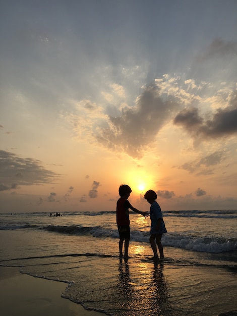 Gens sur la plage de la mer au coucher du soleil s&#39;amuser