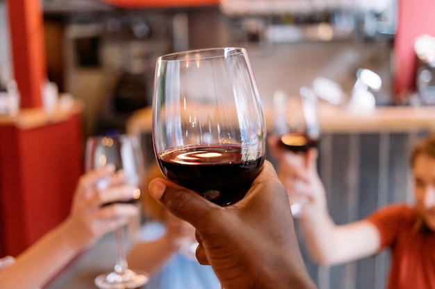 Les gens portant un toast à la main afro-américaine tenant un verre en gros plan sur du vin rouge levant les mains aux acclamations