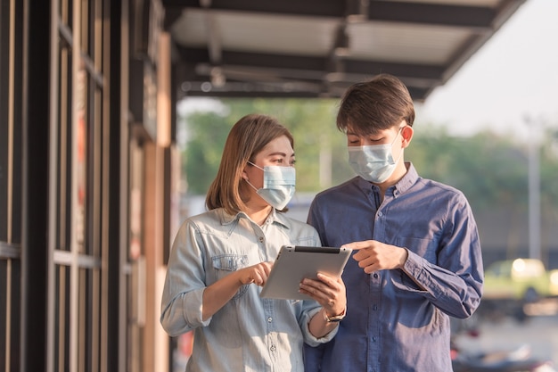 Les gens portent un masque facial pour protéger le coronavirus par la technologie des tablettes