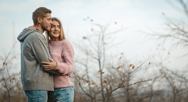 Les gens positifs étreignant sur le ciel et les arbres d'automne