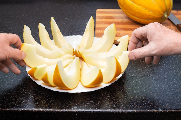 Les gens prennent des tranches de melon juteux mûres de l'assiette avec leurs mains Délicieux aliments sains