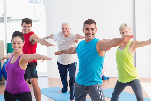 Gens qui font la pose de guerrier dans le cours de yoga