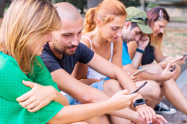 Les gens qui utilisent un téléphone intelligent assis sur la terre ferme