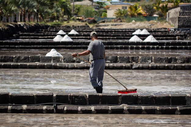 Les gens ramassent le sel par une journée ensoleillée sur les rives de l'océan Indien à Maurice.