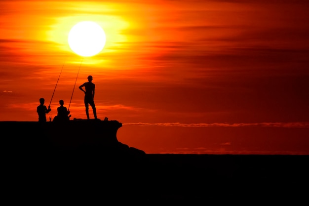 les gens regardent le coucher du soleil sur la plage