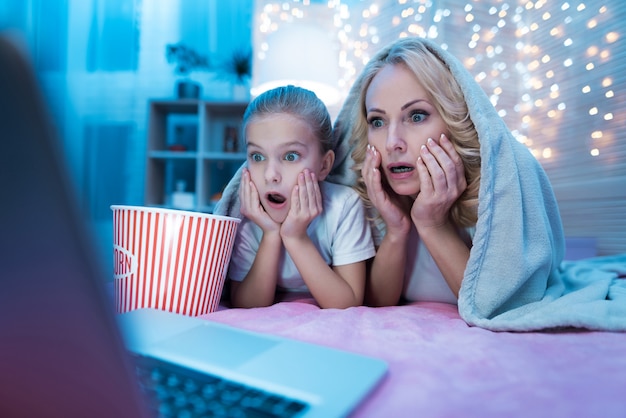 Les gens regardent un film sur un ordinateur portable sur un lit la nuit à la maison.