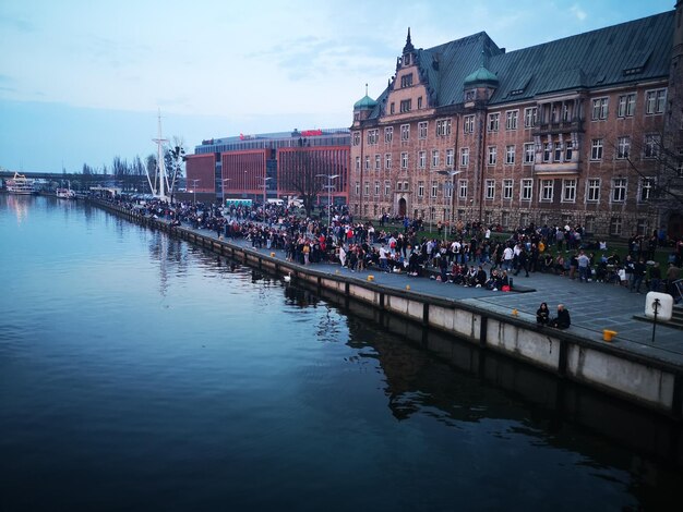 Photo des gens sur la rivière par des bâtiments contre le ciel en ville