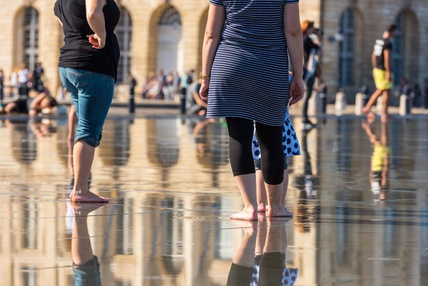 Les gens s'amusant dans une fontaine miroir en face de la Place de la Bourse à Bordeaux, France