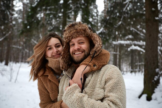 Les gens saison amour et concept de loisirs couple heureux embrassant et riant à l'extérieur en hiver