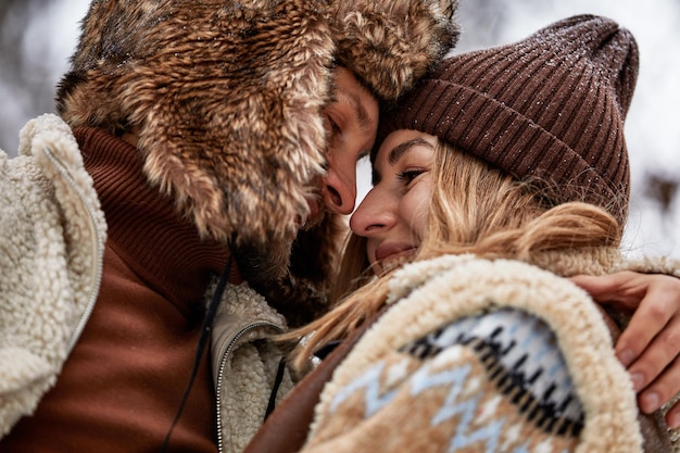 Les gens saison amour et concept de loisirs couple heureux embrassant et riant à l'extérieur en hiver