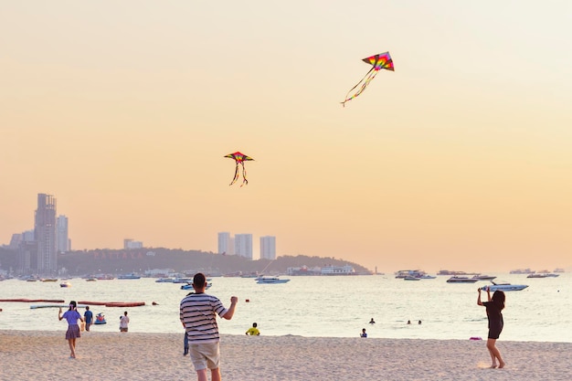 Les gens se détendent sur la côte de la mer fille parlant au téléphone père et fille volant cerf-volant mise au point sélective