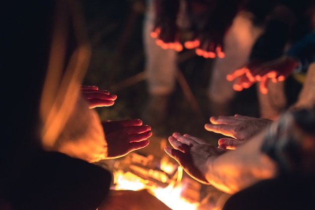 Les gens se réchauffant les mains près du feu de joie. la nuit