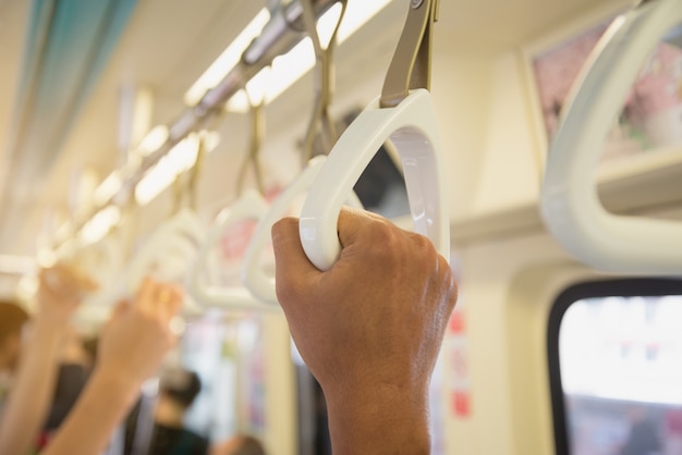 Les gens se tenant sur une poignée de train.