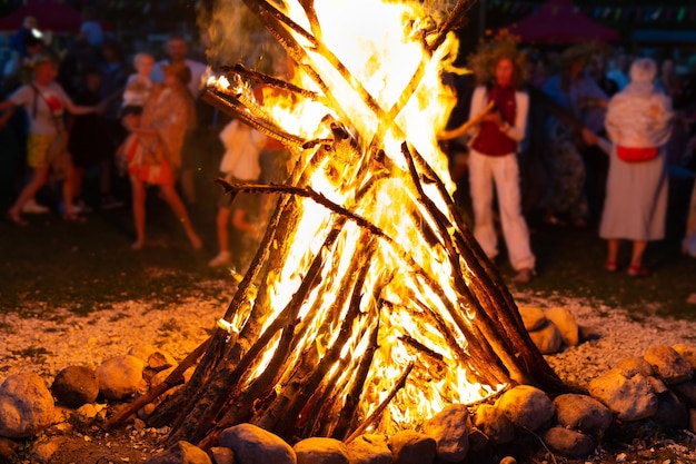 Les gens se tiennent à côté d'un grand feu de joie autour duquel volent des étincelles