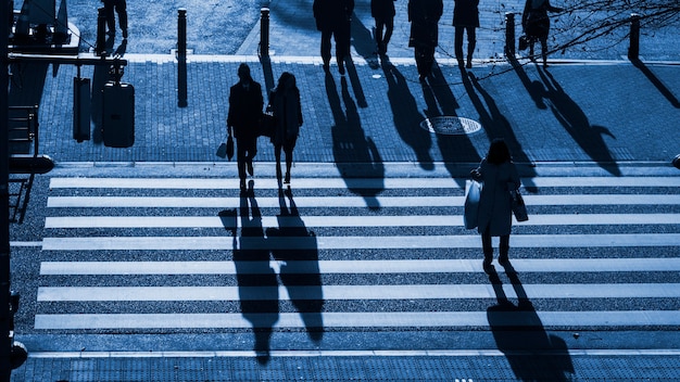 les gens de la silhouette marchent sur le passage pour piétons avec l&#39;ombre des gens