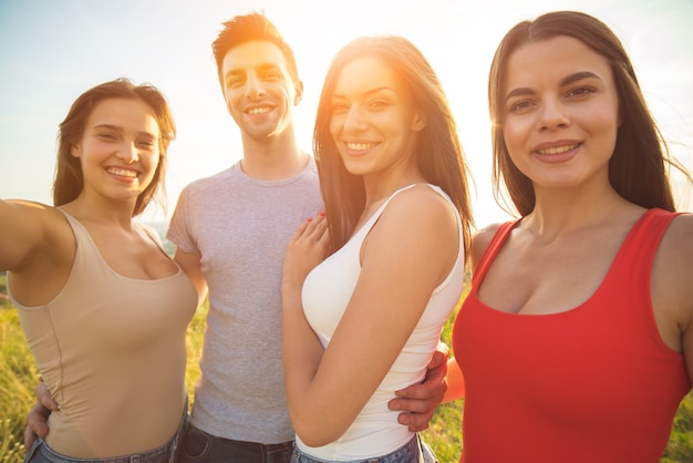 Les gens souriants font un selfie sur fond de soleil