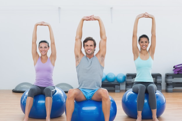 Gens sportifs qui s&#39;étend les mains sur les balles d&#39;exercice au gymnase