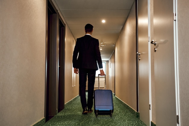 Les gens et la technologie concept heureux jeune homme avec vue arrière de sac de voyage