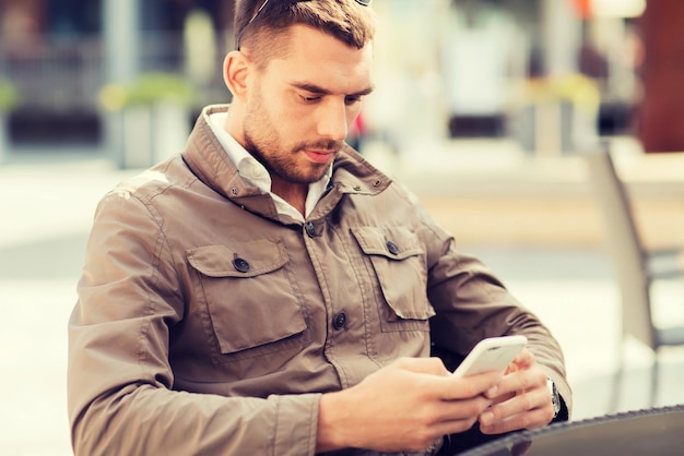 les gens, la technologie, les loisirs et le mode de vie - jeune homme avec message textuel sur smartphone au café de la rue de la ville