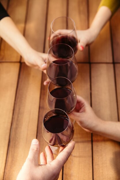 Les gens trinquent avec du vin sur la terrasse d'été du café ou du restaurant. Des amis joyeux et joyeux célèbrent la fête d'été ou d'automne. Gros plan de mains humaines, mode de vie.