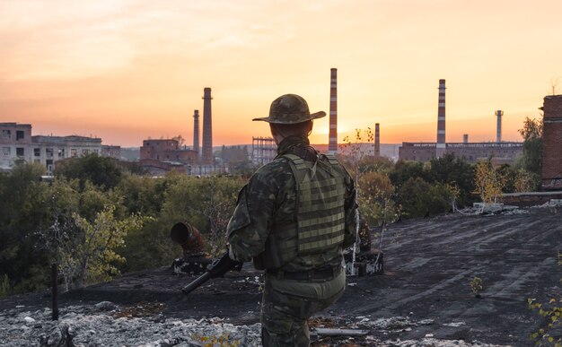 Les gens en uniforme avec des armes dans les ruines