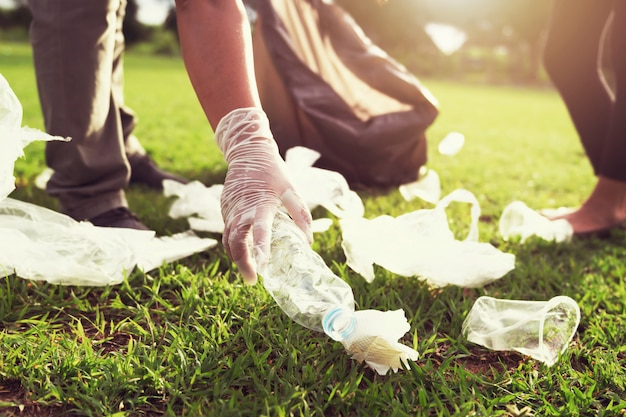 Les gens volontaires gardant une bouteille en plastique de déchets dans un sac noir