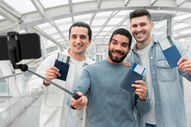 Gens de voyageurs faisant selfie posant avec des cartes d'embarquement à l'aéroport