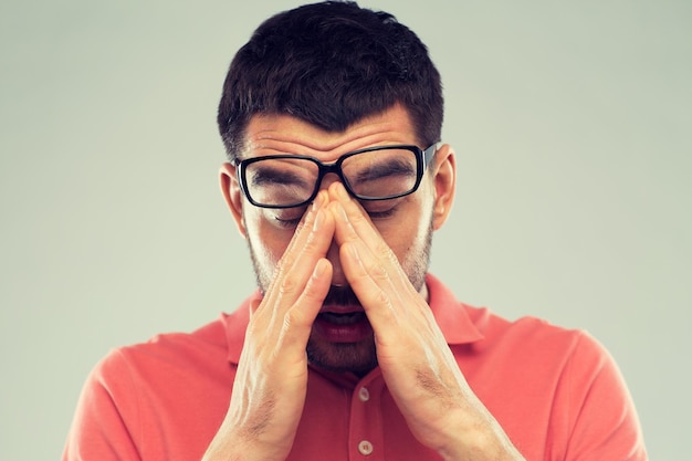 Les gens, la vue, le stress, le surmenage et le concept du problème - un homme fatigué avec des lunettes qui se frotte les yeux